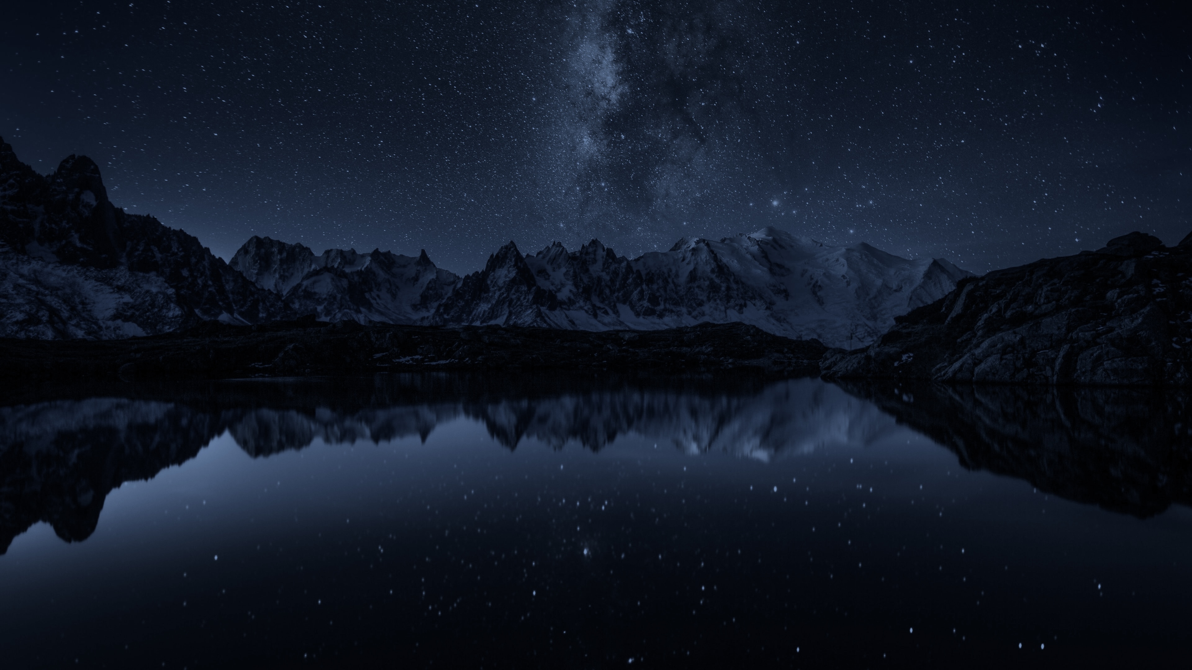 Mountains over a lake under a night sky full of stars